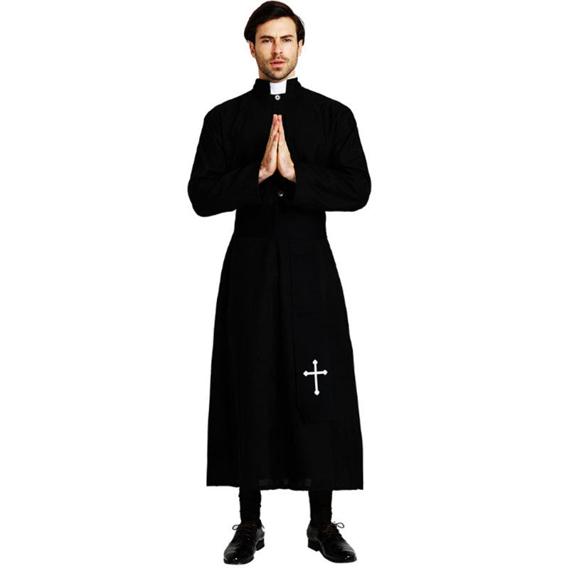 Male model wearing full-length black priest cassock robe with white clerical collar insert and white cross embroidery on lower front, praying hands pose, white background