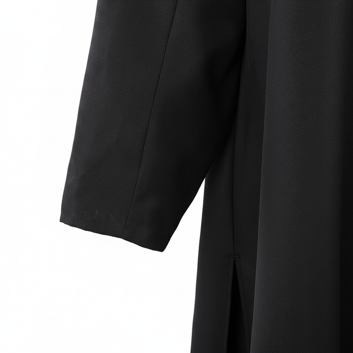 Close-up detail of black cassock robe showing sleeve cuff and side seam stitching on matte black fabric, white background