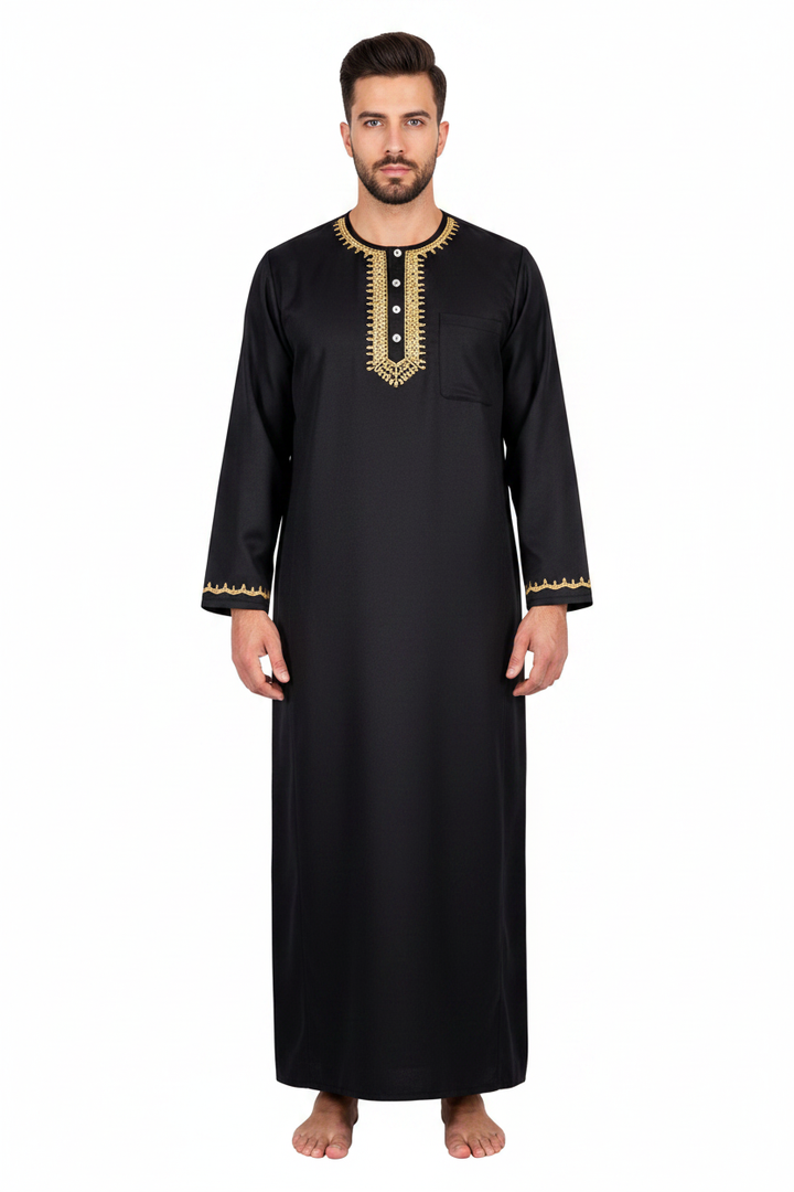 Male model wearing black Islamic thobe jubba with gold U-shape neckline embroidery and button placket, full body front view, white background