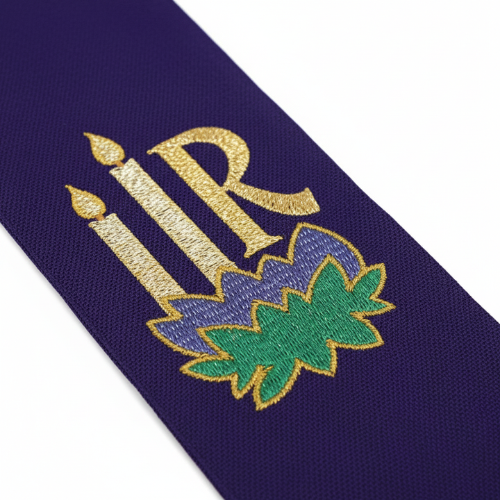 Close-up detail of the purple side of the clergy stole showing gold and green Chi-Rho and candle embroidery, macro shot, white background