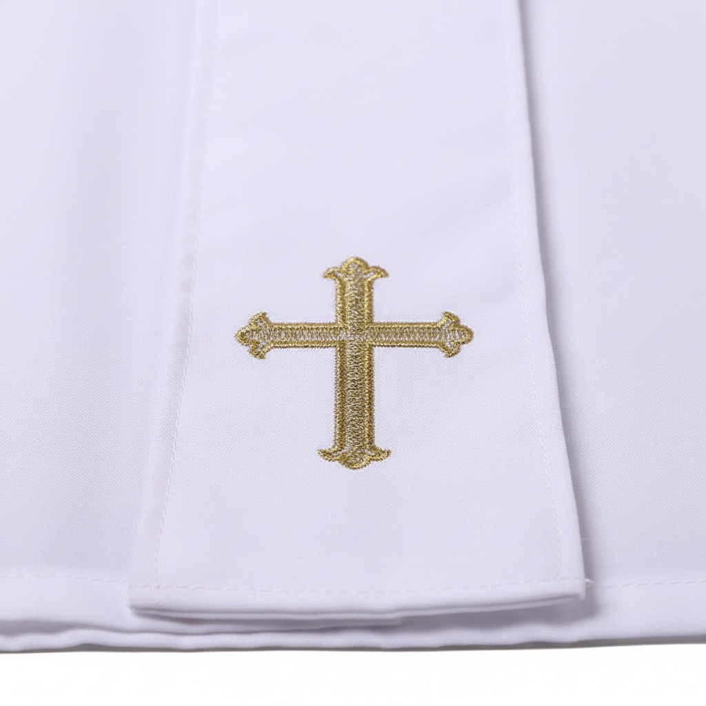 Close-up detail of white cassock robe lower hem showing gold cross embroidery on white fabric, white background