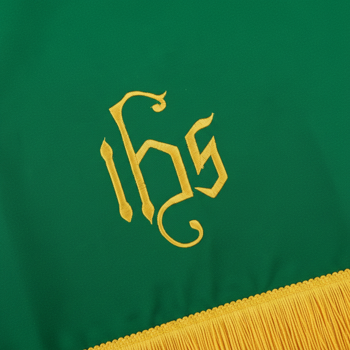 Close-up detail of green church pulpit scarf showing gold IHS embroidery and gold fringe trim, white background