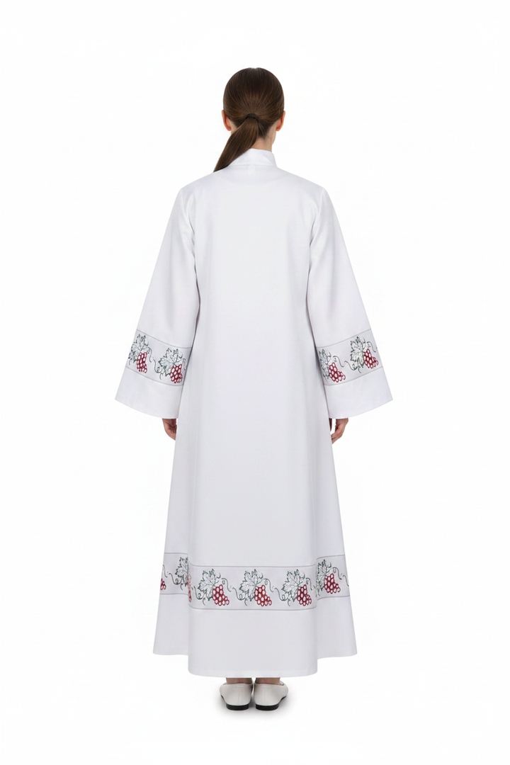 Female model wearing white clergy alb robe with grape vine embroidery cuffs and hem, full body back view, white background